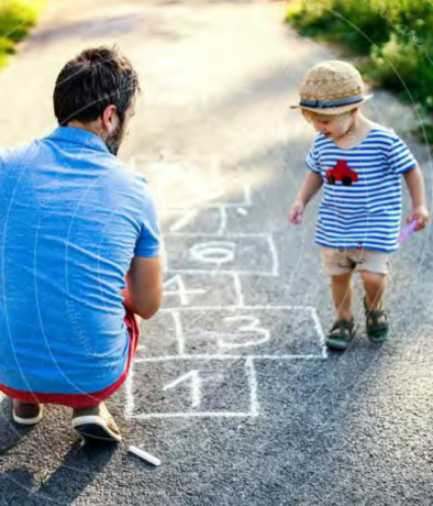 Vater und Kleinkind malen zusammen auf Asphalt