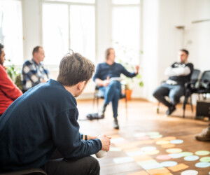 Gruppe mit Dozent in Gruppenarbeit in lichtdurchflutetem Raum