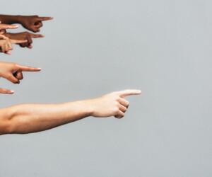 Diverse group of people all pointing to the right, with copy space, on gray background People with their arms outstretched, pointing as if to show the way.