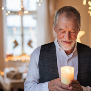 Front view of happy senior man indoors holding candle at Christmas. A front view of happy senior man indoors holding candle at Christmas.