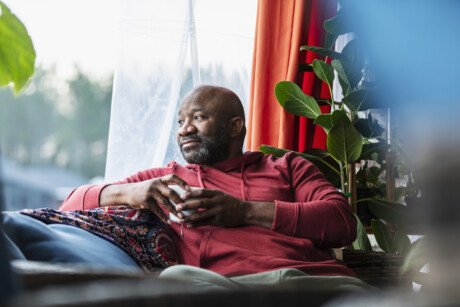 poc-Mann schaut aus dem fenster mit einer tasse tee in der hand - männerdialoge januar 2026