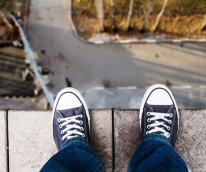 Person in Turnschuhen und Jeans stehen an einem Abgrund Person in Turnschuhen und Jeans stehen an einem Abgrund